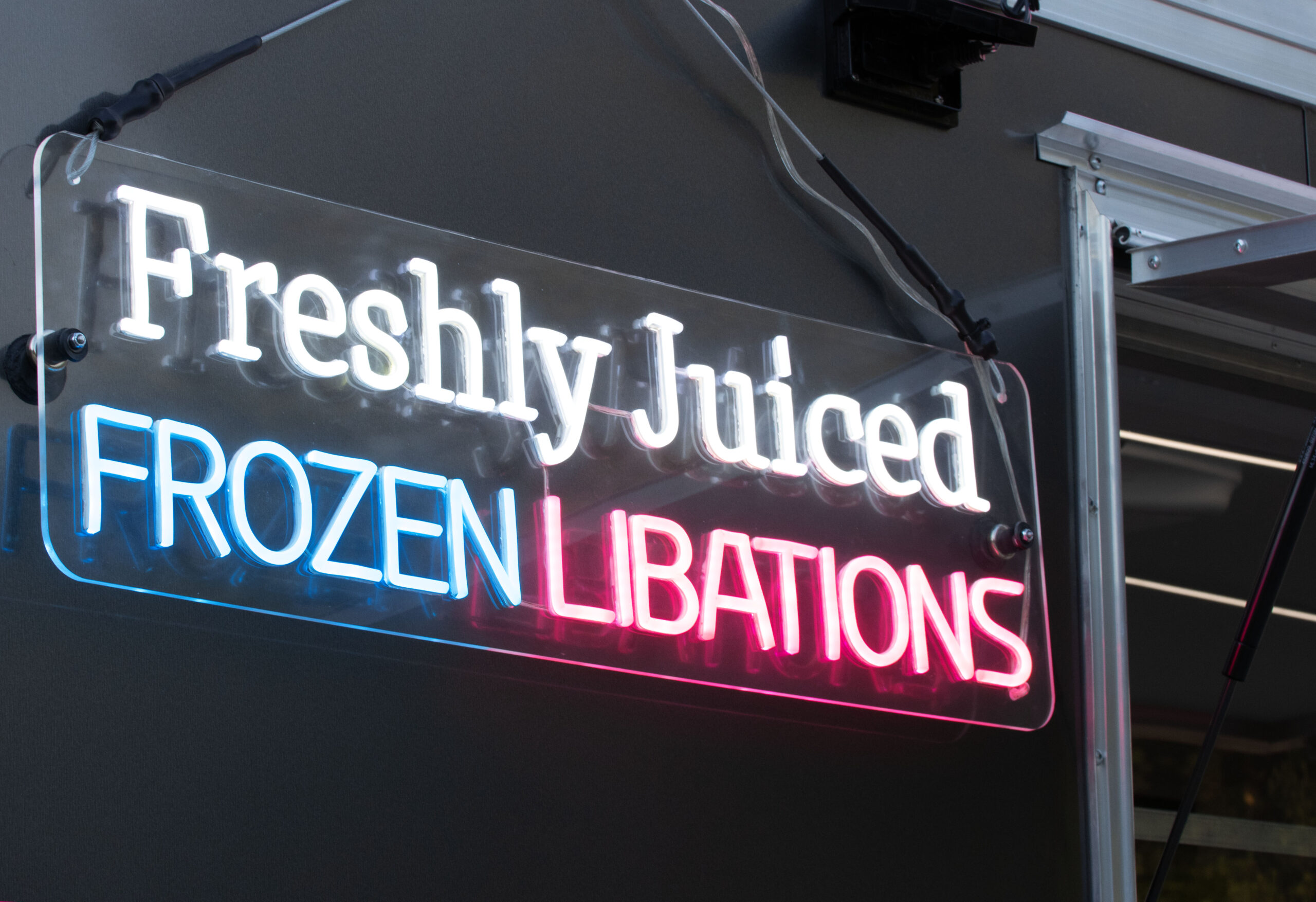 Neon sigh saying "Freshly Juiced Frozen Libations"